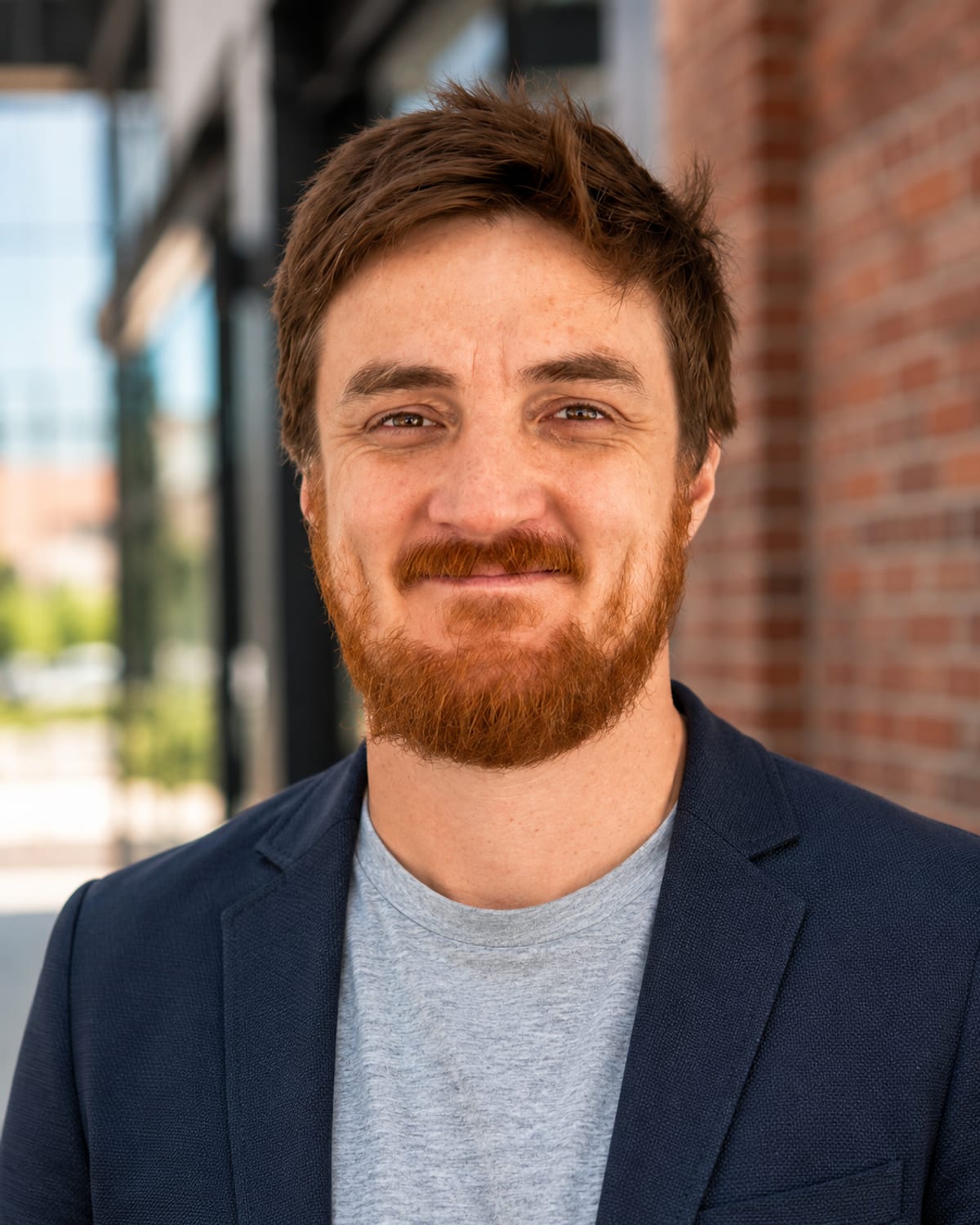 Jonathan Reeve, founder of Kobol Automations, smiling in a navy blazer in front of a brick storefront.